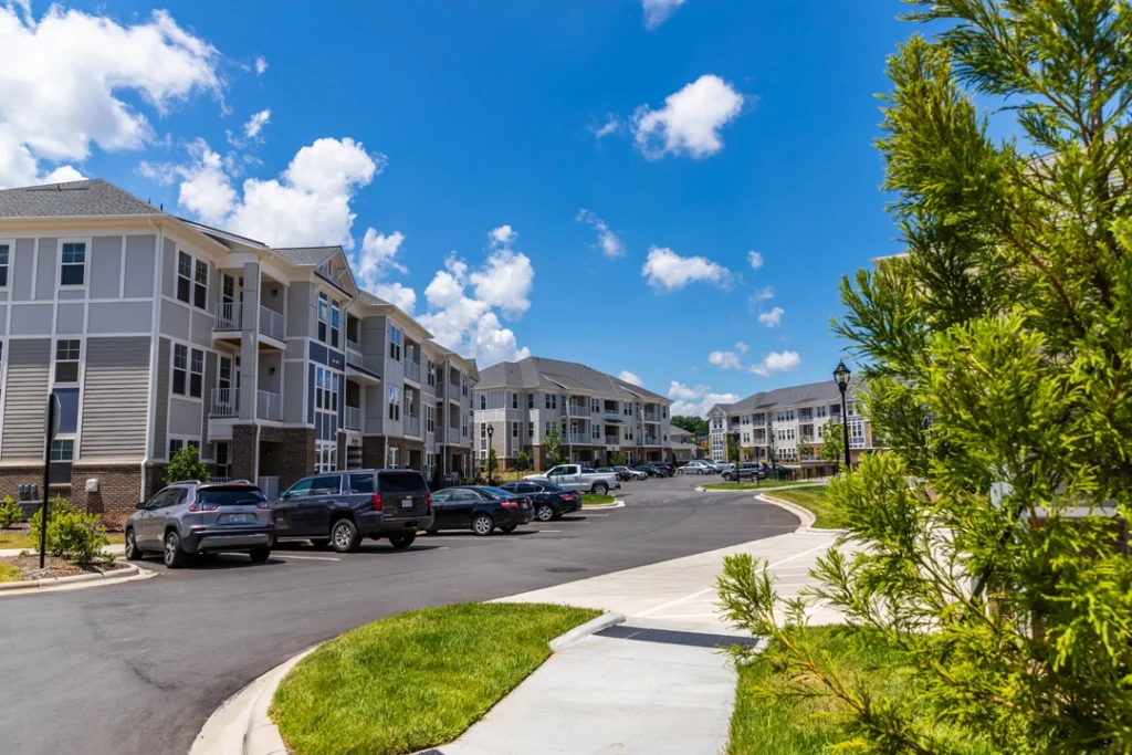 View of residential buildings from the parking lot with tree lined paths