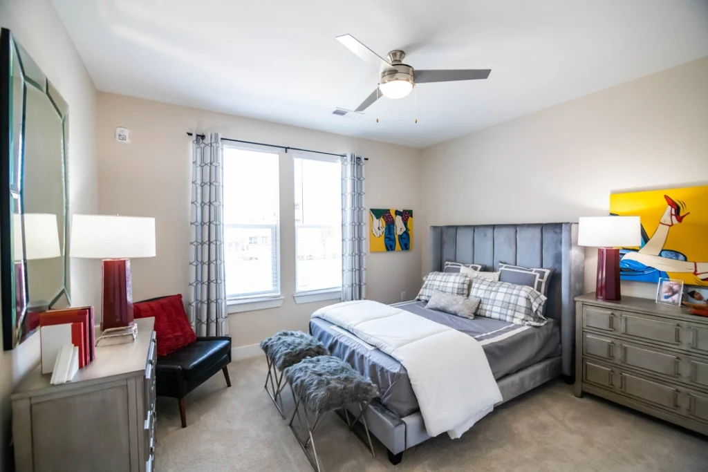 staged bedroom with ceiling fan and large windows