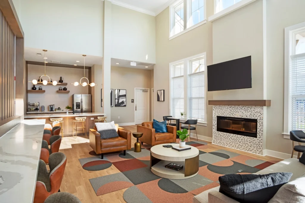 Clubhouse lounge with arm chairs around a fire place and TV